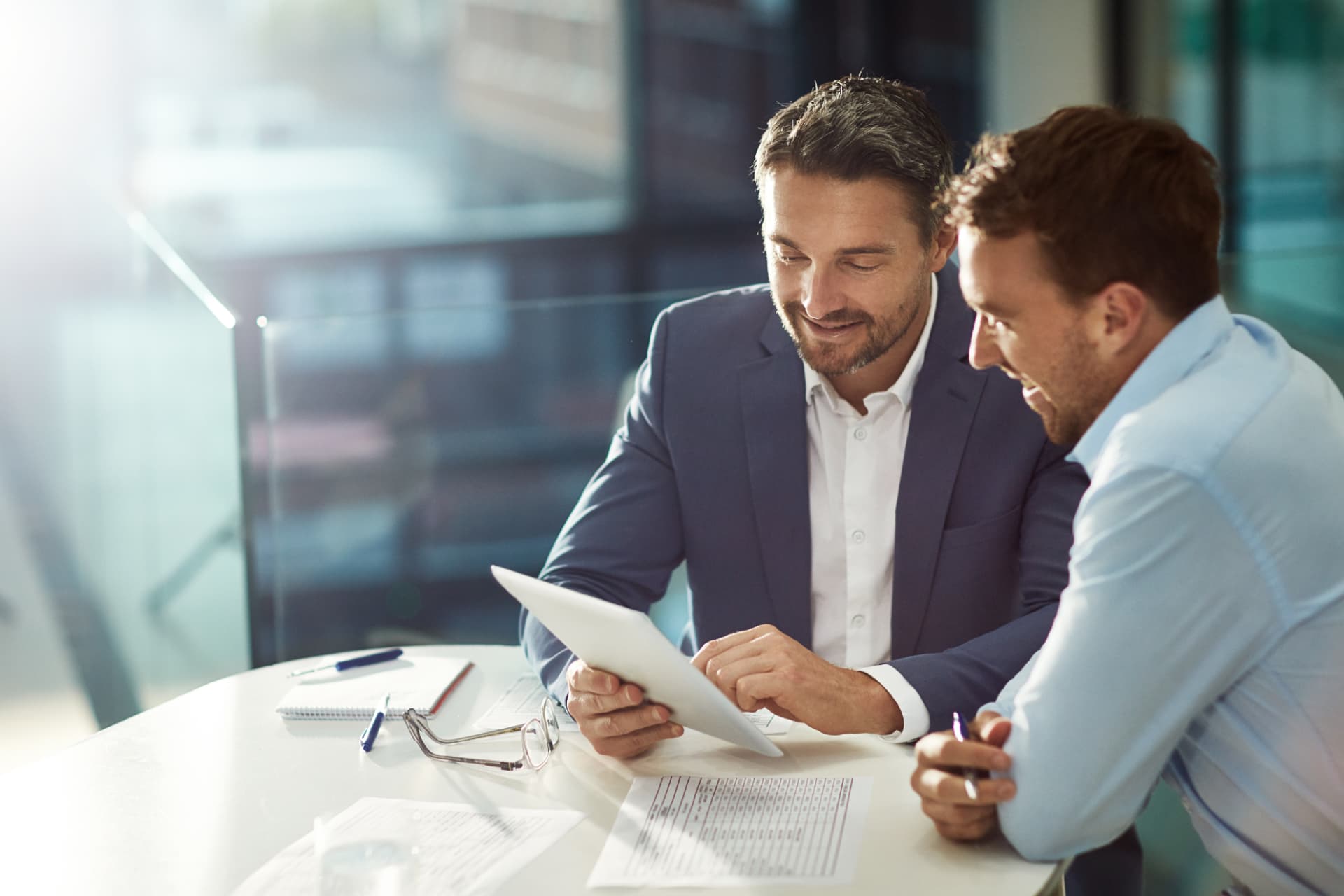 Two advisors reviewing deal information together on a tablet